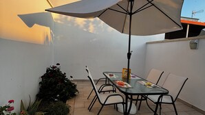 Terassi, jossa on pöytä, tuoleja ja suuri aurinkovarjo.