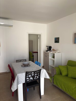 A dining area with a table, chairs, and a green sofa. - The Biancasette, Apartments within walking distance of the sea and a nature reserve (La Strea)
