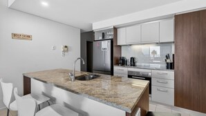 Una cocina moderna con encimera de granito, electrodomésticos de acero inoxidable y armarios blancos.