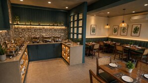 Un restaurante con servicio de buffet, zona de estar y plantas decorativas.