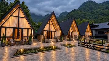 A modern hotel with a courtyard, large windows, and a mountainous backdrop.