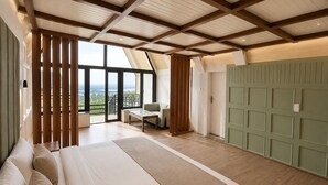 Un dormitorio con una cama grande, vistas por una ventana, un panel de pared verde y una estructura de techo de madera.