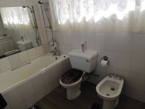 A bathroom with a bathtub, toilet, bidet, and a mirror. - Charming B&B Retreat in Viljoenskroon with Private Entrance (Viljoenskroon)