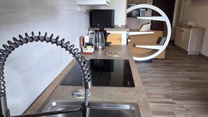 A modern kitchen with a stainless steel sink, a black induction cooktop, and a microwave. - Charming Central Apartment Near Lake Maggiore in Arona (Arona)