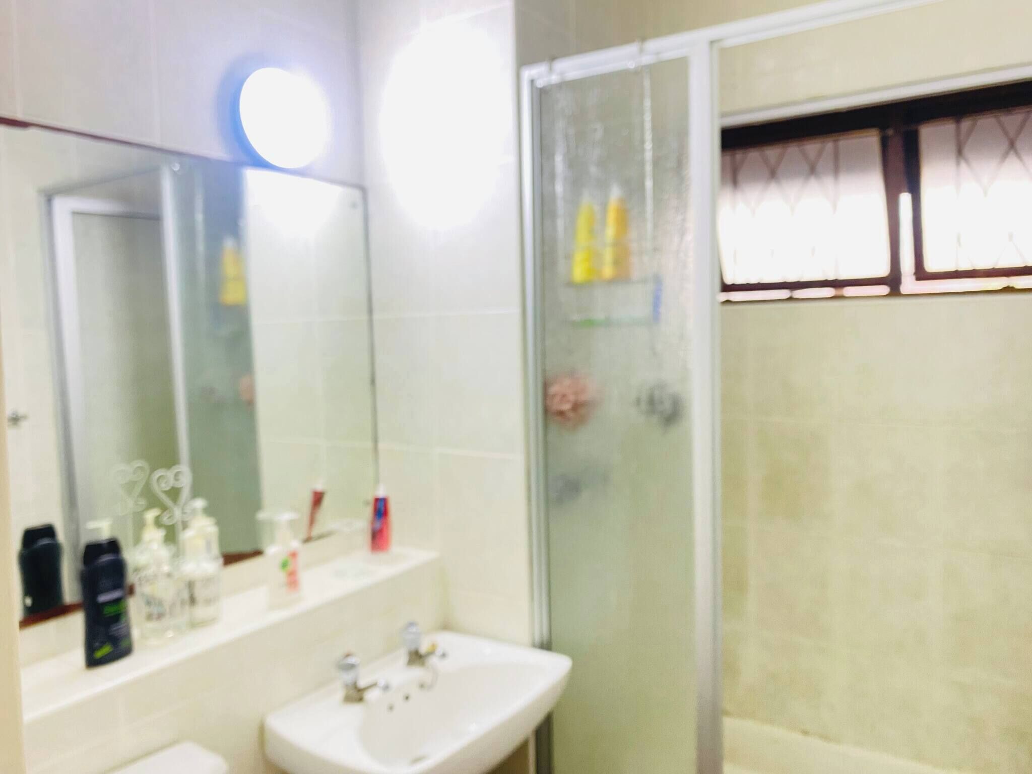 A bathroom with a sink, mirror, and shower.