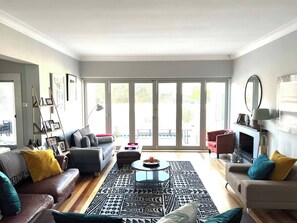 Un salon comprenant un canapé, un pouf, une table basse et un tapis à motifs.