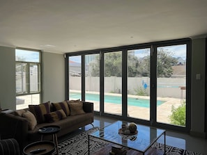 A living room with a large sliding glass door to a backyard with a swimming pool.