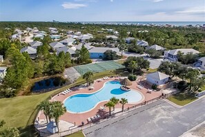 Luchtbeeld van een resort met een zwembad, ligbedden en een tennisbaan.