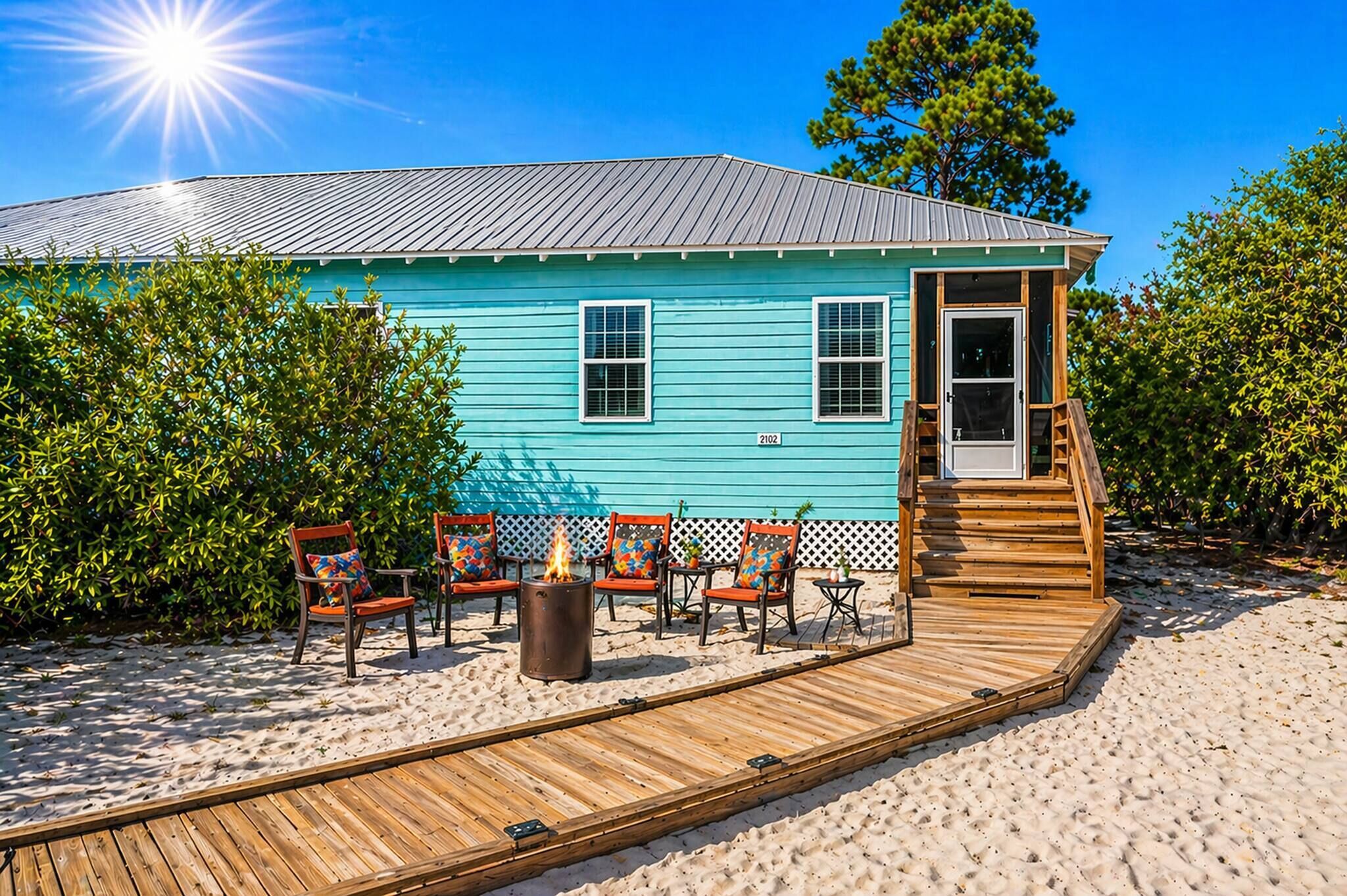 A turquoise house with a deck, outdoor seating, and a fire pit.