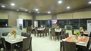 A dining area with multiple tables, chairs, and flower centerpieces. - De Grandeur Tower Apartment (Ojodu)