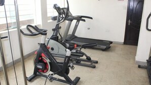 A gym with stationary bikes, a treadmill, and a mirrored wall. - De Grandeur Tower Apartment (Ojodu)