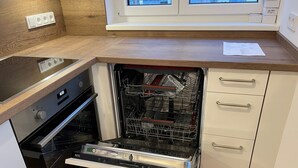 A kitchen with a dishwasher, oven, and wooden countertop.