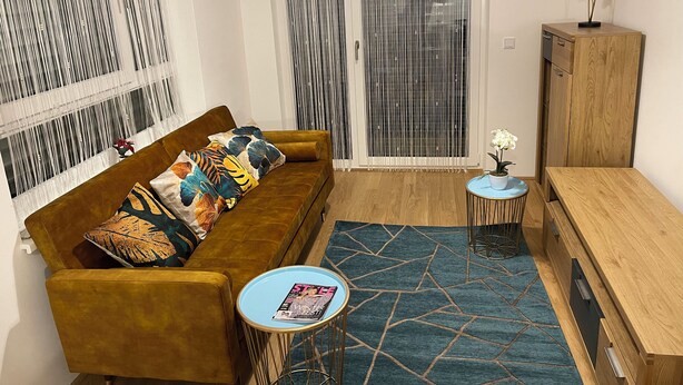 A living room with a sofa, a coffee table, a cabinet, and a patterned rug.