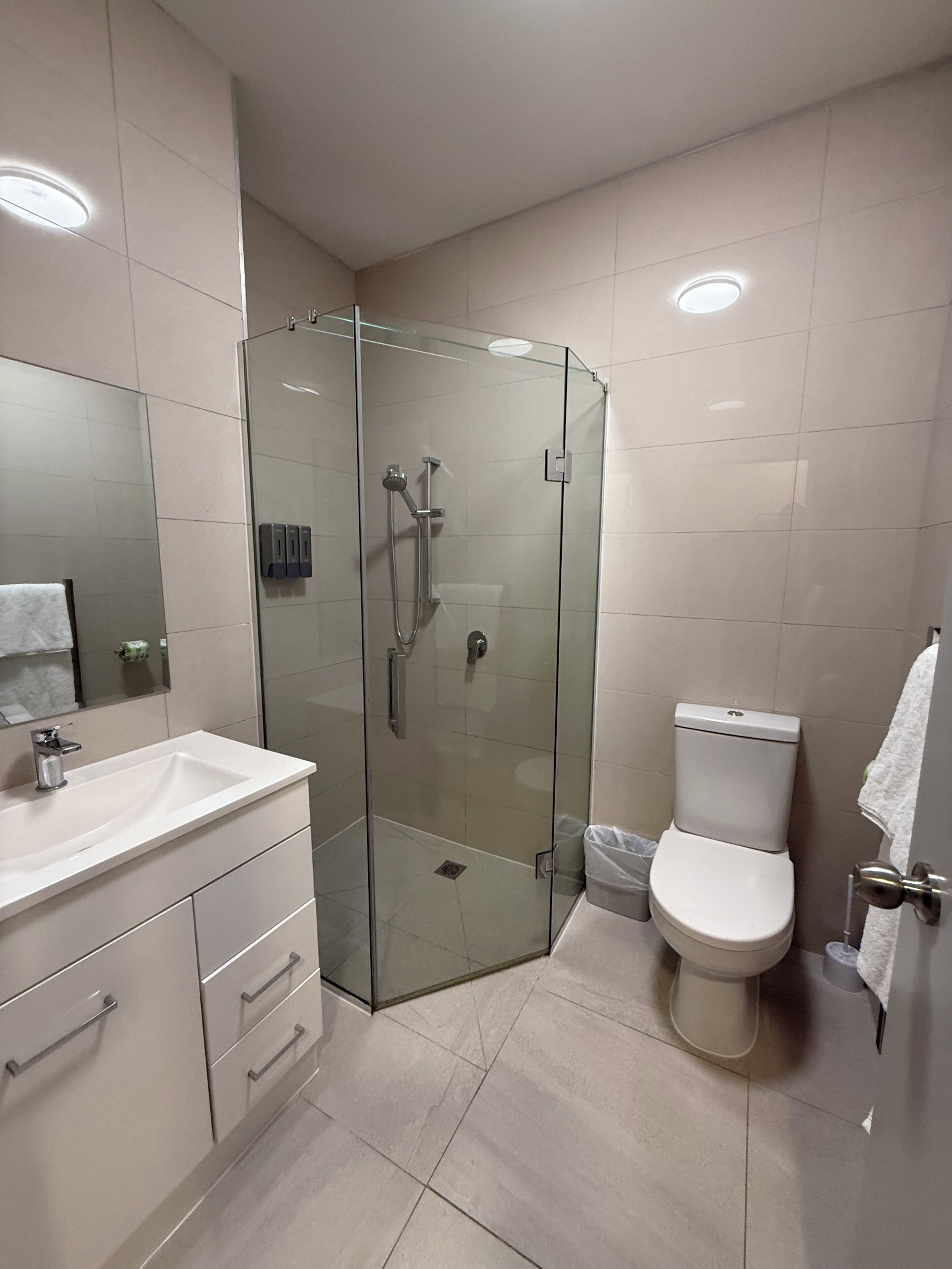 A modern bathroom with a glass-enclosed shower, a white sink, and a toilet.