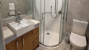 A modern bathroom with a glass-enclosed shower, a white sink, and a toilet.