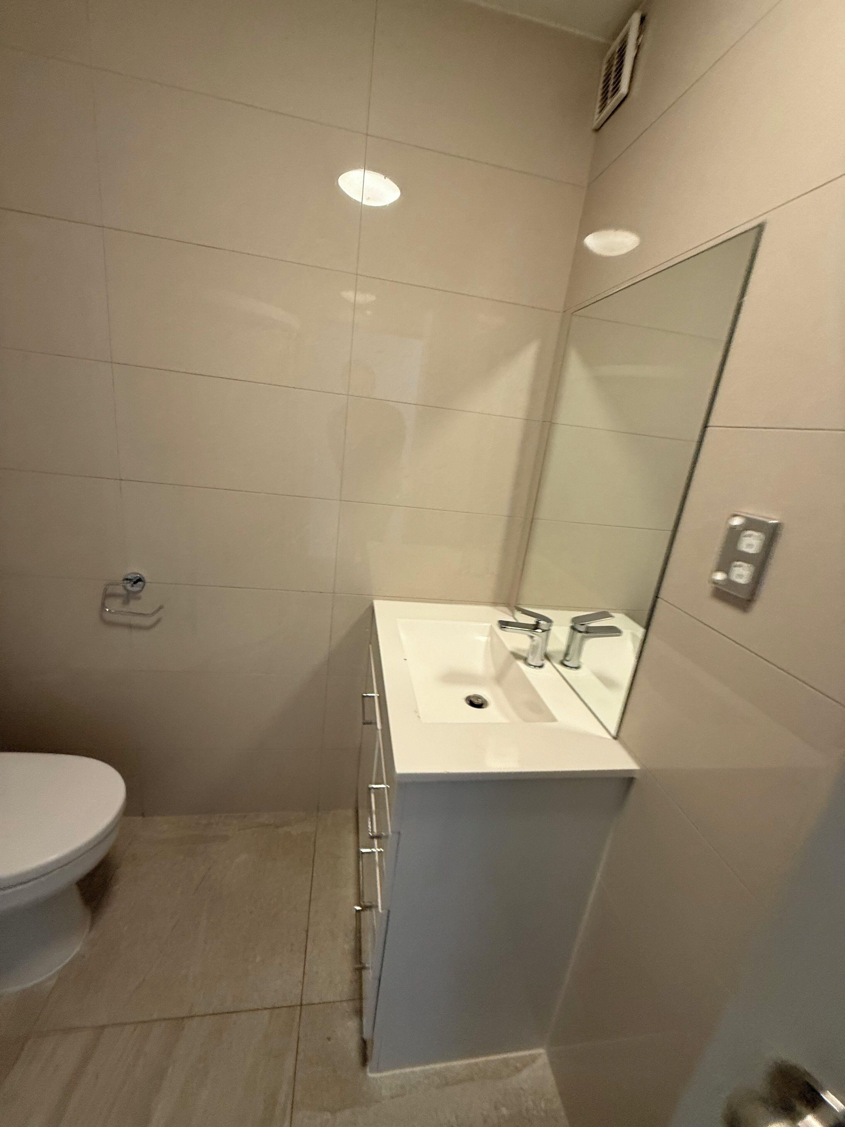 A bathroom with a white sink, mirror, and toilet.