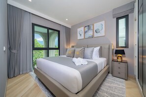Ein modernes Schlafzimmer mit einem großen Bett, einem Nachttisch, einem Fenster mit Vorhängen und Bildern an der Wand.