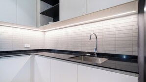 Una cucina moderna con mobili bianchi, un piano di lavoro nero e un lavello in acciaio inossidabile.