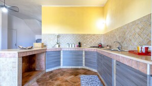 A kitchen with a curved countertop, built-in cabinets, a sink, and a tiled backsplash. - Apartment 'Casa Orizzonte Anglona' with Private Terrace, Garden and Wi-Fi (Nulvi)