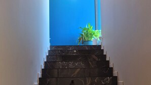 Eine Marmortreppe führt zu einem Raum mit blauer Akzentwand und einer hängenden Leuchte.