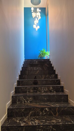 A marble staircase leading to a room with a blue accent wall and a hanging light fixture. - Exceptional contemporary villa with infinity pool - Pont du Gard (Remoulins)