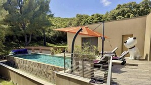 Ein Swimmingpool mit Sonnenschirm, Liegestühlen und einer Hundestatue.