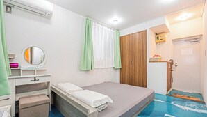 Een slaapkamer met een bed, een kaptafel met spiegel, een houten garderobe en een badkamer met douche.