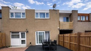 Un edificio residenziale con patio in mattoni, recinzione in legno e antenna parabolica.