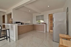 Una cocina moderna con una isla central, un refrigerador y un comedor con una mesa y sillas de madera.