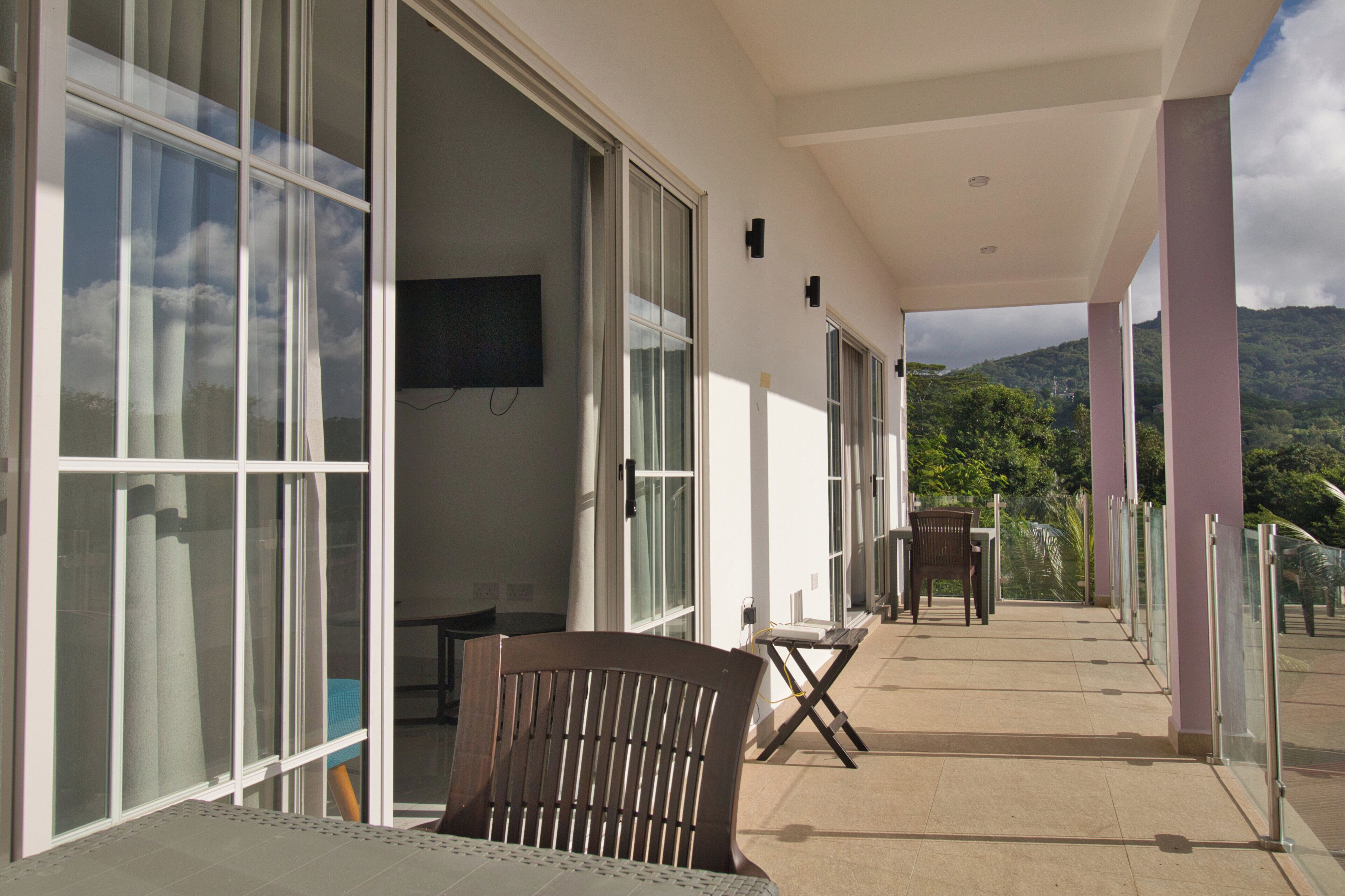A balcony with a chair, a table, and a TV mounted on the wall.