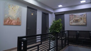 A hallway with grey walls, black doors, and two paintings. - Karaman Hotel (Tashkent)