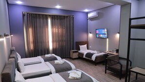 A hotel room with two beds, a desk, a chair, a TV, and a window with curtains. - Karaman Hotel (Tashkent)
