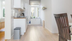 Moderni keittiö, jossa on valkoiset kaapit, puinen työtaso ja näkymä ruokailutilaan.