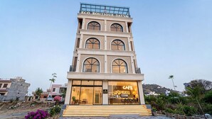A multi-story building with a cafe on the ground floor, featuring large windows and a staircase leading to the entrance. - Eco Boutique Satva Udaipur - Vegetarian with all Options (Udaipur)