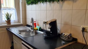 Une cuisine équipée d’un évier, d’une machine à café et d’une fenêtre avec une plante.