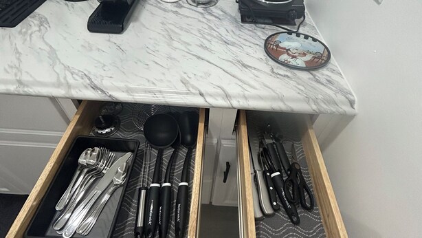 A kitchen with a marble countertop, a coffee maker, a kettle, a toaster, and a drawer with utensils. - Sweet home (Brandon)