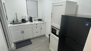 A compact kitchen with white cabinets, a black refrigerator, and a microwave. - Sweet home (Brandon)