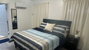 A bedroom with a bed, bedside tables, a nightstand, a mirror, and a door. - Sweet home (Brandon)