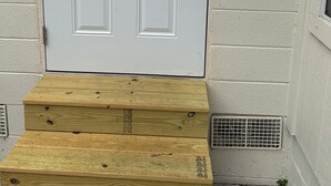 A white door with a keypad lock, a small window, and a wooden step leading to the door. - Sweet home (Brandon)