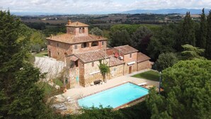 A stone building with a swimming pool, surrounded by trees and a view of distant hills. - Casale Le Rondini with a swimming pool and private garden (LUCIGNANO)