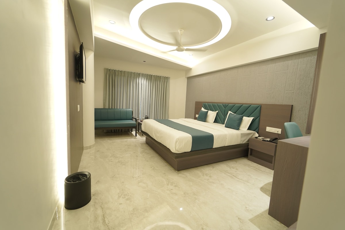 A modern hotel room with a large bed, a desk, a chair, and a television.
