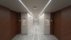 Un pasillo con puertas de madera, letreros numerados y piso de mármol.