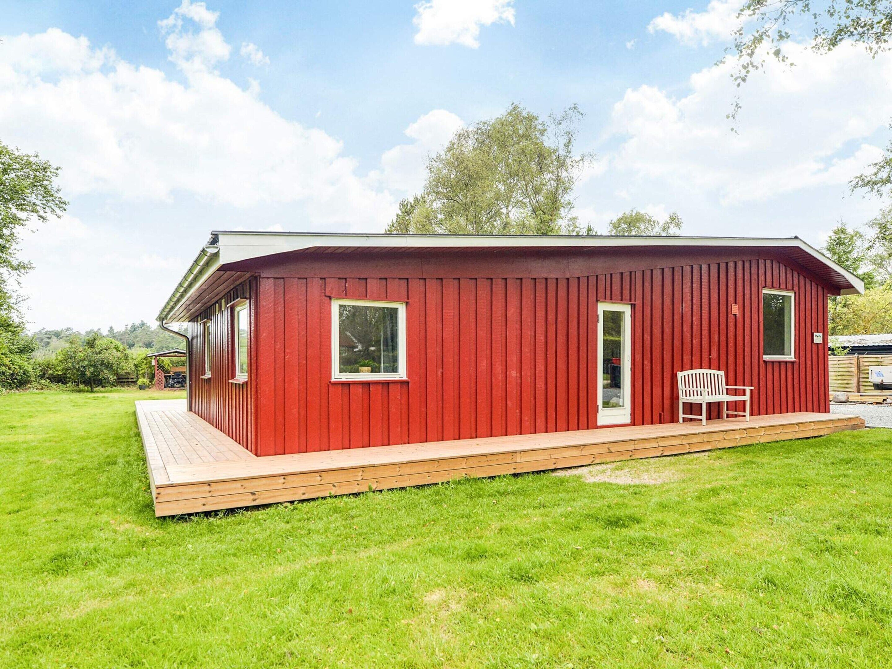 En rød træbygning med veranda, dør og vindue.