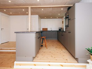 Eine moderne Küche mit grauen Schränken, einem Holzstuhl und Holzboden.