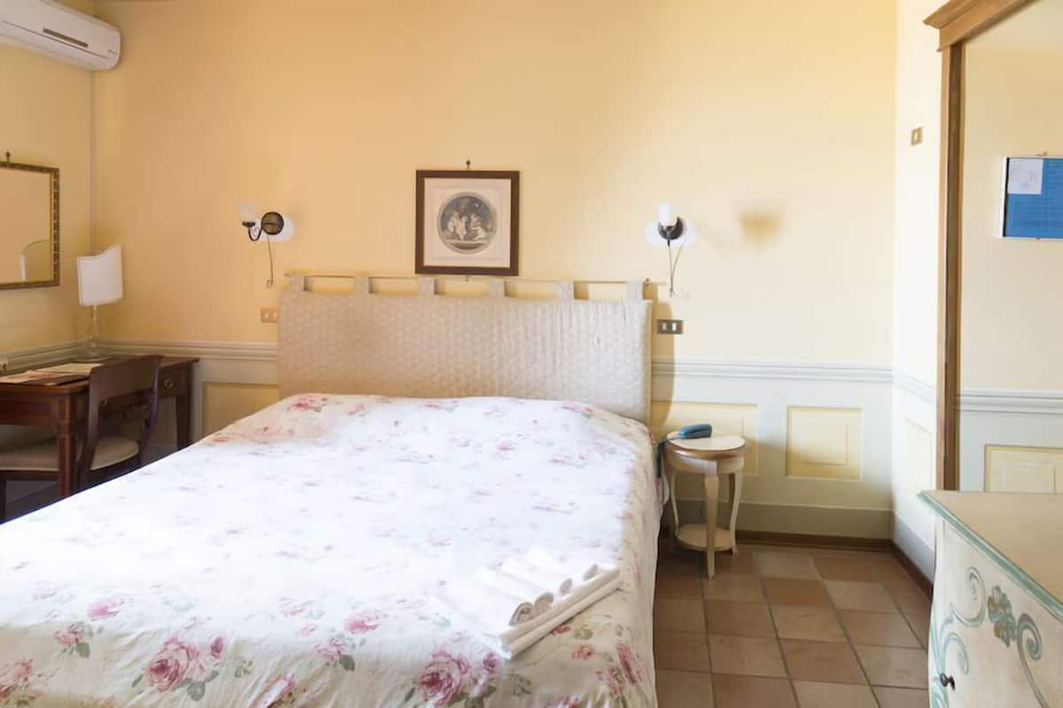 Un dormitorio con cama, mesitas de noche, escritorio y silla.