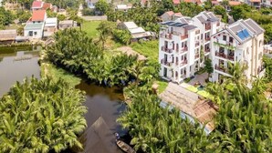 A residential area with a river, palm trees, and multi-story buildings. - Ony Retreat Villas (Da Nang)