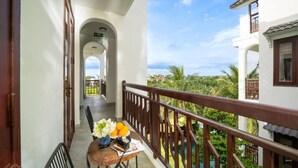 A balcony with a table, chairs, and a view of greenery and a pool. - Ony Retreat Villas (Da Nang)