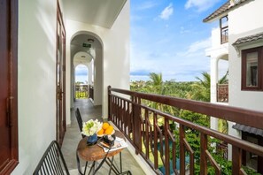 A balcony with a table, chairs, and a view of greenery and a pool. - Ony Retreat Villas (Da Nang)