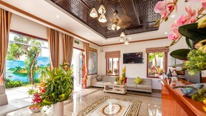 A hotel lobby with a sofa, a coffee table, a reception desk, and a large window with curtains. - Ony Retreat Villas (Da Nang)