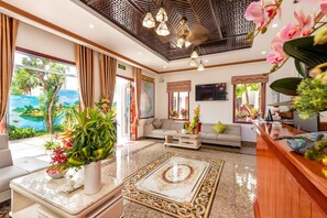 A hotel lobby with a sofa, a coffee table, a reception desk, and a large window with curtains. - Ony Retreat Villas (Da Nang)